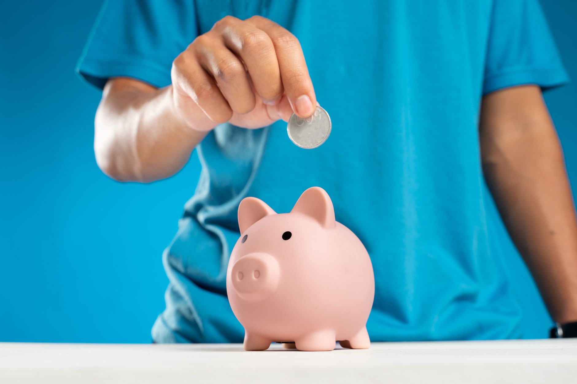 a person putting a coin in a piggy bank