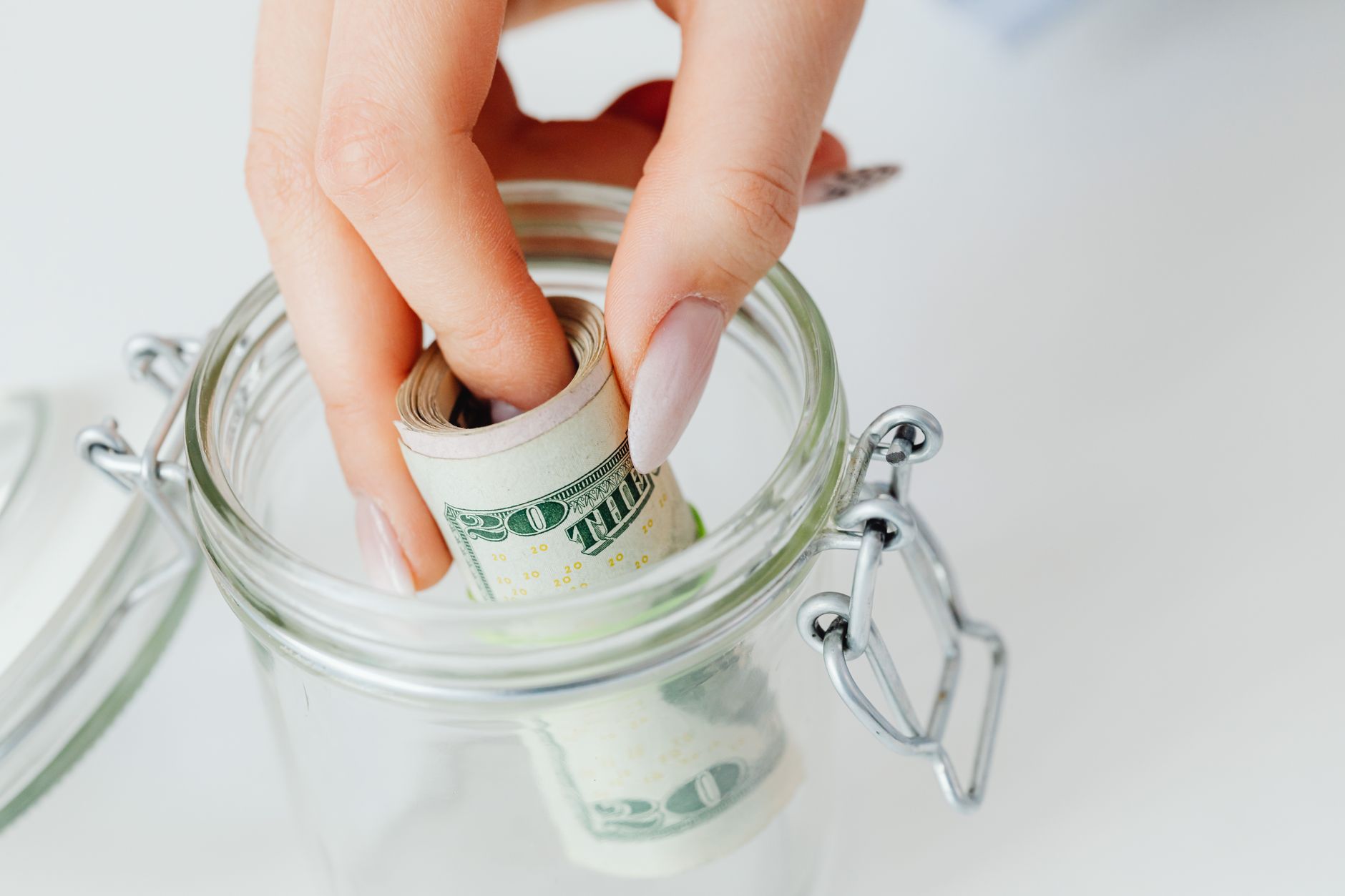 close up shot of a person saving money in the glass jar
